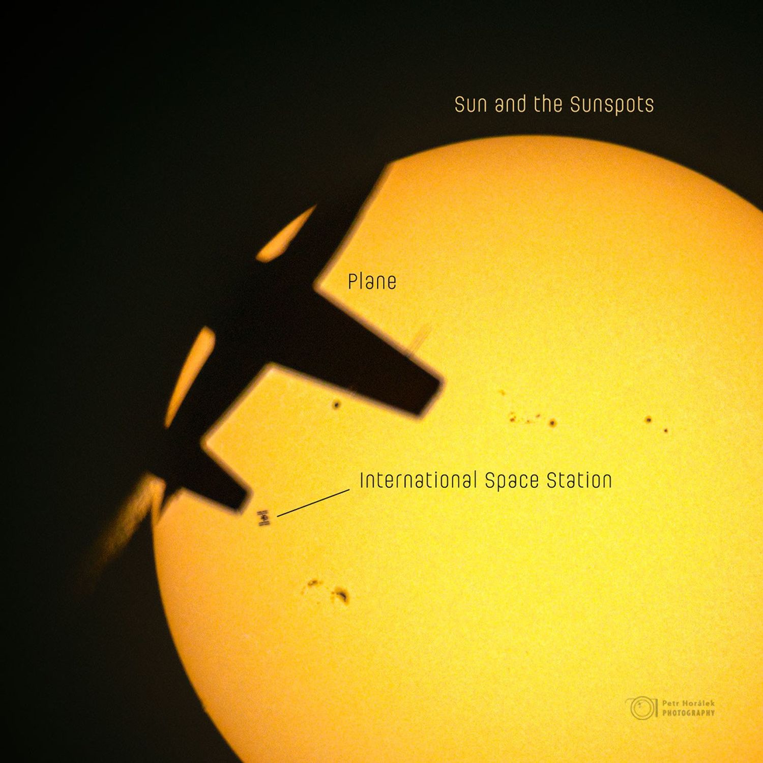 An image of the Sun is shown with several dark silhouettes superposed. On the upper right is an airplane, on the right is the International Space Station, and across the Sun are several sunspots. Please see the explanation for more detailed information.